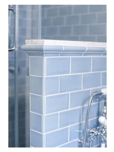 a blue tiled bathroom with a shower head and hand held faucet in the corner