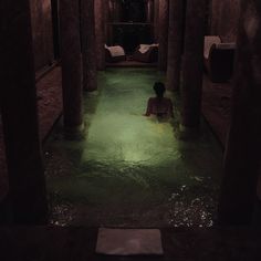 a woman is sitting in the middle of a hot tub with water running through it