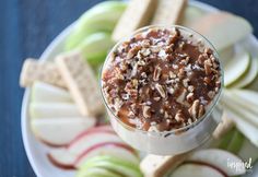 a dessert in a glass dish with nuts and chocolate on top, surrounded by crackers