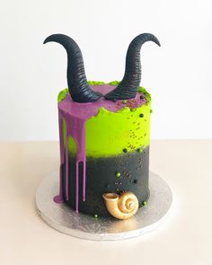 a cake decorated with green and black icing has horns sticking out of the top