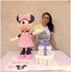 a woman standing next to a minnie mouse cake