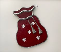 a red glass ornament with snowflakes hanging from it's side