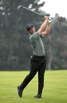 a man swinging a golf club on top of a green field