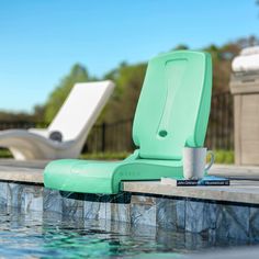 two lounge chairs sitting on the edge of a swimming pool next to a book and coffee cup