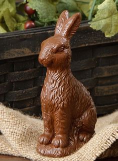 a chocolate bunny sitting on top of a table next to some lettuce and carrots