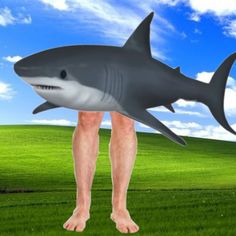 a man standing in the grass with a large shark on his back and feet up