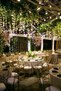 tables and chairs are set up for an event with lights strung from the ceiling above them