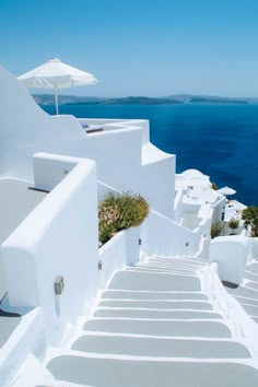 stairs leading up to the top of a building with an umbrella over them and blue water in the background