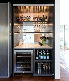 If you plan on adding in many new appliances or lighting when renovating, it may mean your home needs to be rewired. Cool bar set up with drinks fridge, wine fridge, pocket door, mirrored splashback, marble benchtop, charcoal veneer shelving, backlights Modern Home Bar Designs, Home Bar Kitchen, Home Bar Areas, Home Bar Cabinet, Bar Mini, Home Kitchen Bar, Home Bar Rooms, Modern Home Bar, Home Wine Cellars