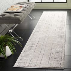 a large white rug on the floor in front of a window with a bench and potted plant