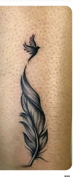 a black and white feather tattoo on the thigh