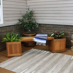 a wooden bench sitting on top of a hard wood floor next to potted plants