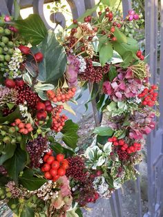 a wreath with berries and leaves hanging on a gate