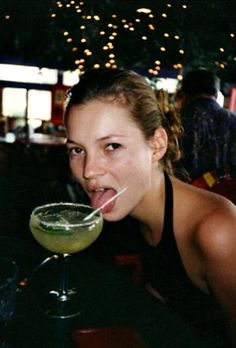 a woman drinking from a martini glass with a straw sticking out of it's mouth