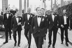 a group of men in tuxedos walking down a sidewalk