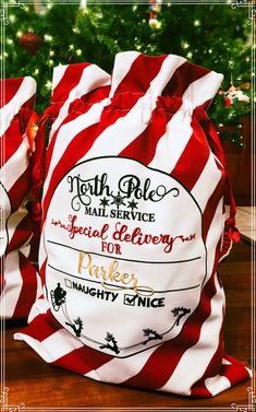 two red and white striped bags sitting on top of a table next to a christmas tree