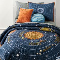 a bed covered in blue and orange bedspread with space themed pillows on it