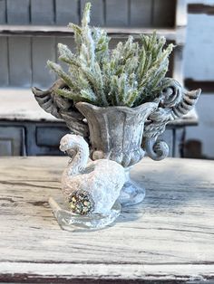 a vase filled with plants sitting on top of a wooden table