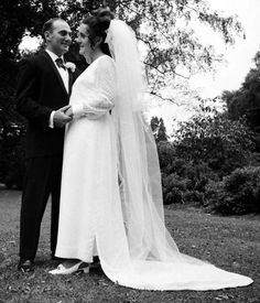 a bride and groom standing together in the grass