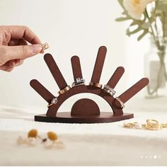 a person is placing rings on top of a wooden ring holder with flowers in the background