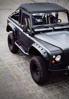 a black jeep parked on the side of a road next to a cement wall,