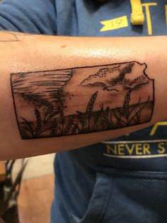 a man with a tattoo on his arm that has an image of a mountain in it