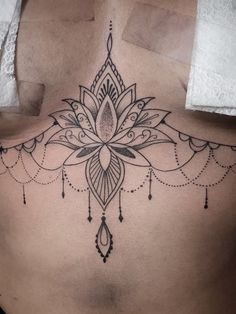 a woman's lower back with a tattoo design on her stomach and an intricate flower in the center