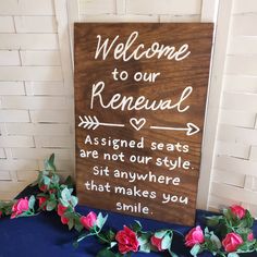 a wooden sign that says welcome to our renewal with roses on the table next to it