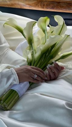 the bride is holding her wedding bouquet in her hand while she sits down with her hands on her lap