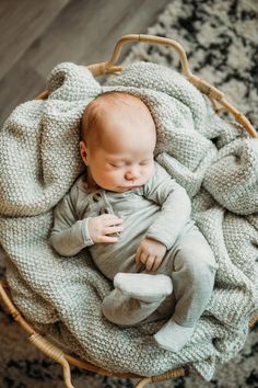 a baby is sleeping in a basket on the floor