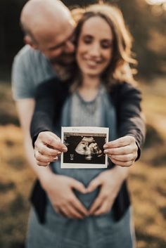 a man and woman holding an old photo in their hands