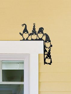 an image of halloween decorations on the window sill in front of a yellow house