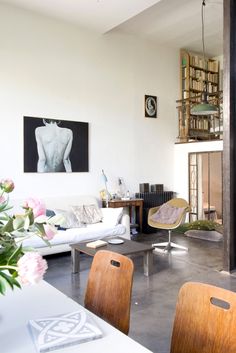 a living room filled with furniture and a fire place next to a white table topped with flowers