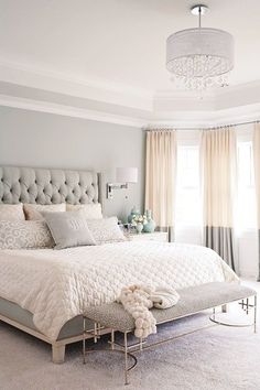 a bedroom with gray walls and white bedding in the center, along with a chandelier hanging from the ceiling