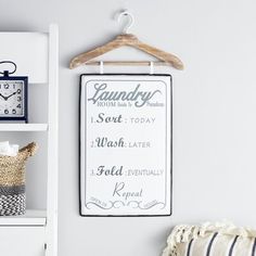 a laundry room sign hanging on the wall next to a shelf with a clock and other items