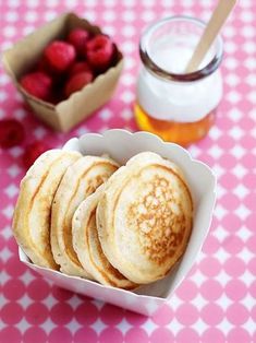 some pancakes and raspberries in a bowl on a pink checkered tablecloth