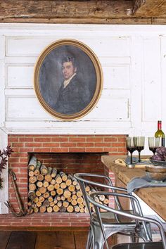 a room with a fire place and paintings on the wall above it, as well as wine glasses