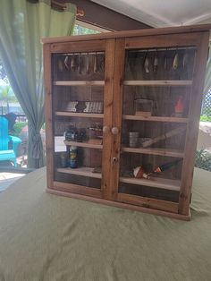 a wooden cabinet sitting on top of a bed next to a green curtained window