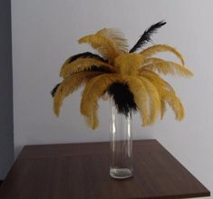 there is a vase with some yellow and black feathers in it on top of a table