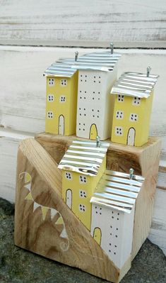 three little houses made out of wood sitting on the side of a building with white and yellow paint