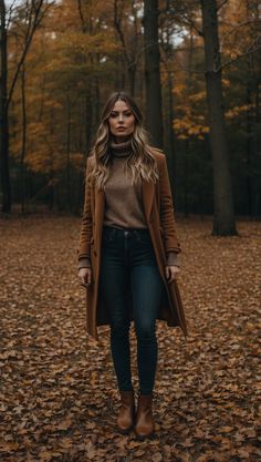 Woman wearing a stylish fall outfit with a camel coat, turtleneck sweater, dark jeans, and brown boots in a forest with autumn leaves. Cute Fall Layering Outfits, Classy Women Winter Outfit, Cute Autumn Winter Outfits, Pedicure Outfit Fall, Different Looks For Women, Shop Fall Outfits, Classy Outfits For Women Fall, Rain Boot Outfit Fall, Cute Fall Office Outfits