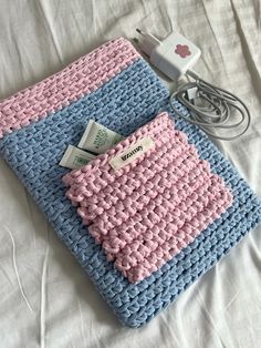 a blue and pink crocheted blanket sitting on top of a bed next to an ipod