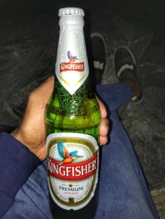 a person holding a beer bottle in their hand with the label kingfisher on it