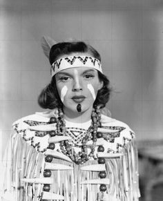 an old black and white photo of a woman wearing native american clothing with feathers on her head