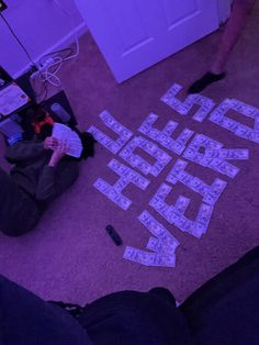 two people sitting on the floor with letters cut out of them to spell out words