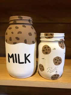 two jars with cookies painted on them sitting on a shelf