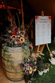 there are many flowers in the buckets on the grass near a sign that says welcome to our guests