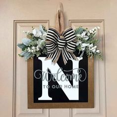 a door hanger with a monogrammed letter n on it and flowers hanging from the front