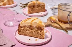 three slices of cake on pink plates with spoons and cups in front of them