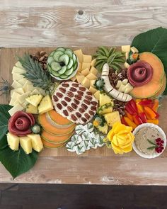 an assortment of cheeses and fruits on a cutting board